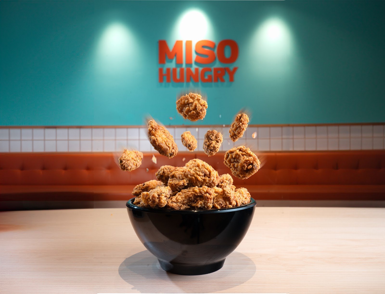 Floating crispy chicken above a black bowl for Miso Hungry